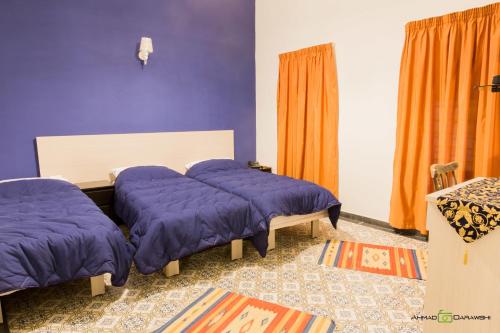 a bedroom with two beds with purple sheets and orange curtains at Al-Hakim Boutique Hotel Old Town Nazareth in Nazareth