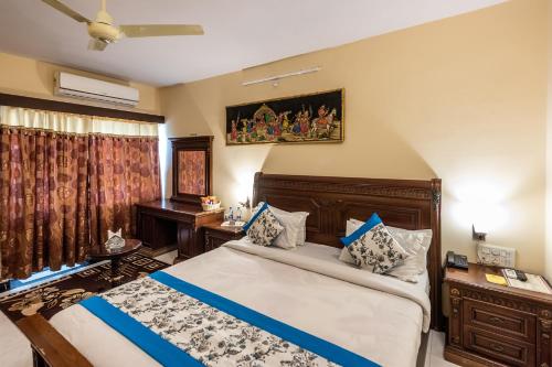 a bedroom with a bed and a desk and a window at Yorkshire Inn in Mount Ābu