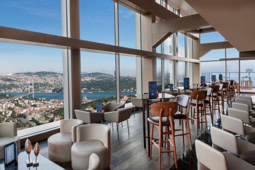 um restaurante com cadeiras e mesas e janelas grandes em Renaissance Istanbul Polat Bosphorus Hotel em Istambul