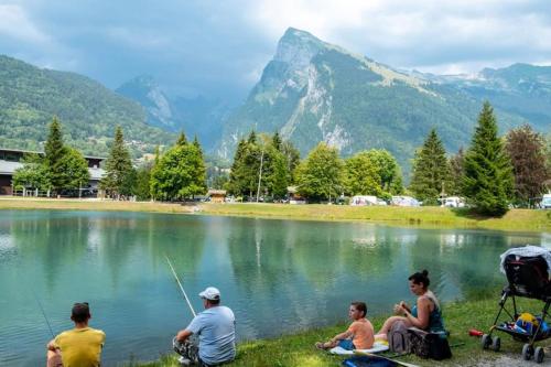 a group of people sitting around a lake fishing at Bungalow 3 chambres pour 6 pers avec Climatisation Camping 3 etoiles in Samoëns
