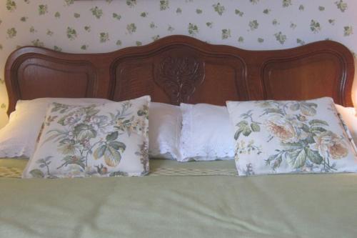 1 cama con almohadas blancas y cabecero de madera en La CoLLina del Moro, en Bracelli