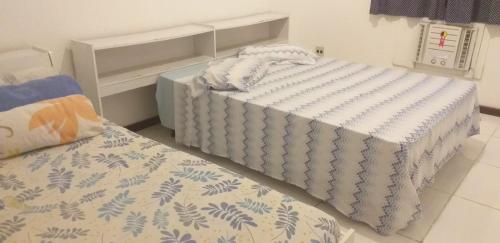 CASA DE PRAIA CABO FRIO في كابو فريو: سريرين في غرفة صغيرة مع مفارش نوم