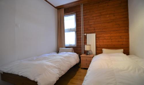two beds in a room with wooden walls at Haus Viols 46 in Savognin