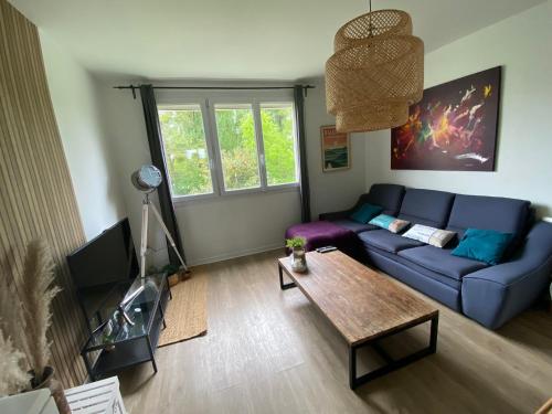 - un salon avec un canapé bleu et une table dans l'établissement Superbe appartement au calme avec parking gratuit., à Mérignac