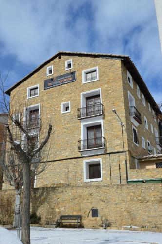 a large brick building with a tree in front of it at Hostal de Montaña la Casa Grande in Nogueruelas