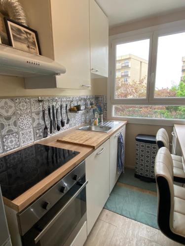 une cuisine avec un évier et une cuisinière dans l'établissement Superbe appartement au calme avec parking gratuit., à Mérignac