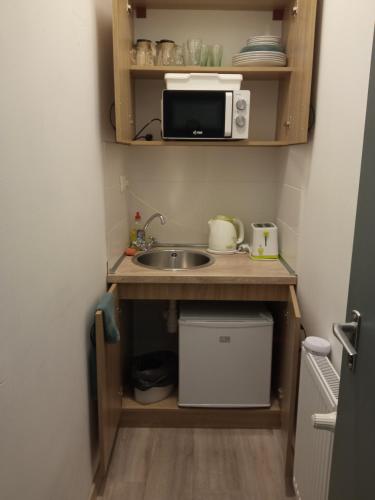a small kitchen with a sink and a microwave at Cherry II Apartman in Eger
