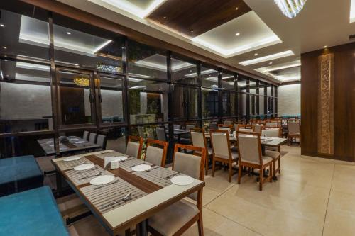 a restaurant with wooden tables and chairs and windows at Blisss Hotel, Kolhapur in Kolhapur