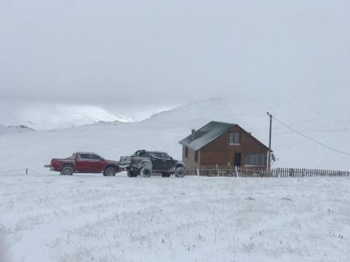 zwei Autos, die vor einem Haus im Schnee geparkt sind in der Unterkunft KULAT DAĞ EVİ in Gumushane