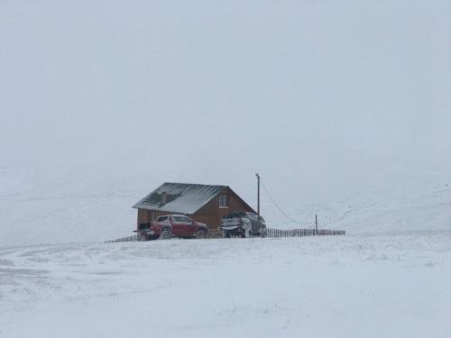 ein rotes Auto, das neben einem Haus im Schnee parkt in der Unterkunft KULAT DAĞ EVİ in Gumushane