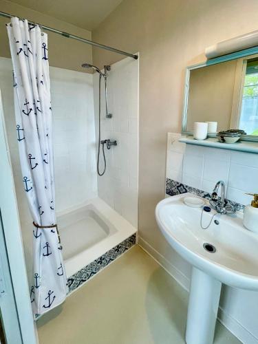 une salle de bain blanche avec un lavabo et une douche dans l'établissement Maison Collinée, à Rostrenen