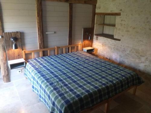1 dormitorio con 1 cama con manta blanca y azul a cuadros en Gite du moulin, en La Mothe-Saint-Héray