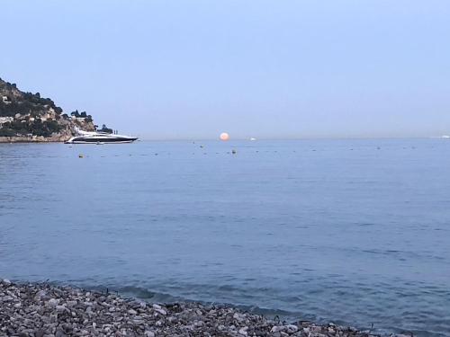 a boat in the water with a rocky beach at Ezevacances Studio Capuccino vue mer 5 mn plage 7 mn gare Wifi in Èze