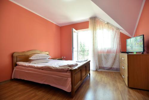 a bedroom with orange walls and a bed and a window at Vila Roberta in Buşteni