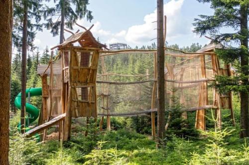 a playground with a tree house in the woods at Apartmán s terasou a výhledem na jezero Lipno in Kovářov