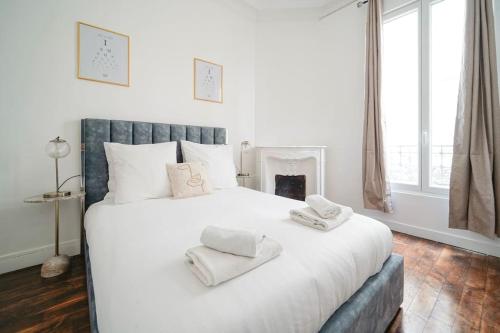 une chambre avec un grand lit blanc avec des serviettes dessus dans l'établissement Niepce - Blue flat next to Avenue du Maine, à Paris