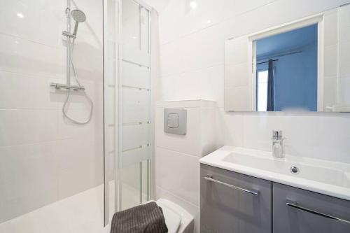 une salle de bain blanche avec une douche et un lavabo dans l'établissement Niepce - Blue flat next to Avenue du Maine, à Paris