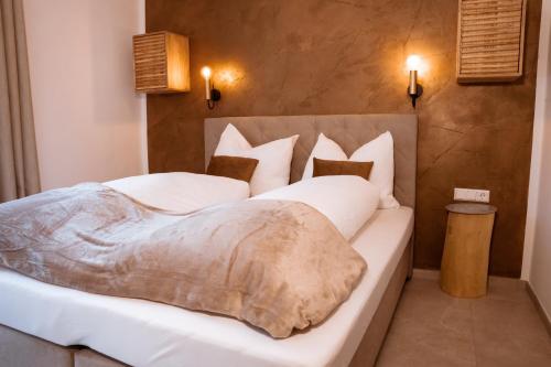 ein Schlafzimmer mit einem großen Bett mit weißer Bettwäsche und Kissen in der Unterkunft Pyramidenkogel Lodge in Keutschach am See
