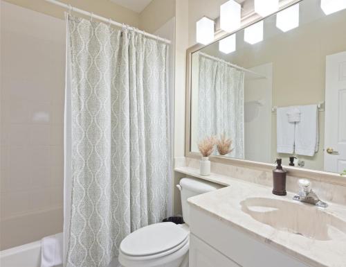 a bathroom with a toilet and a sink and a mirror at Lely Greenlinks Top Floor - on Golf Course, Minutes from Beaches, Downtown! in Naples