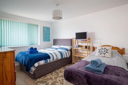 a bedroom with two beds and a television in it at Fairwinds,Bigbury on sea ,Three-bed Beach House in Bigbury on Sea