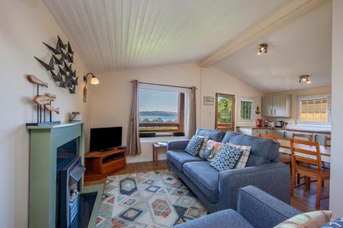 a living room with a blue couch and a fireplace at Appin Holiday Homes -Caravans, Lodges, Shepherds Hut and Train Carriage stays in Appin