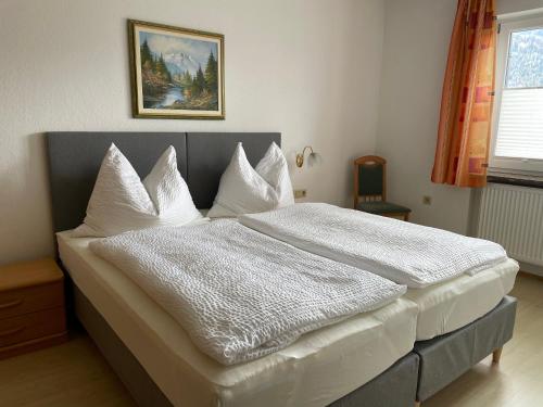 um quarto com uma cama grande com lençóis e travesseiros brancos em Am Randersberg - Wohnung Nr 2 em Grossgmain