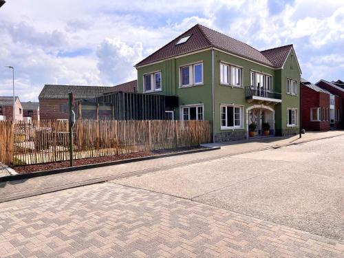 une maison verte avec une clôture dans une rue dans l'établissement Time - Out Genoelselderen, à Riemst