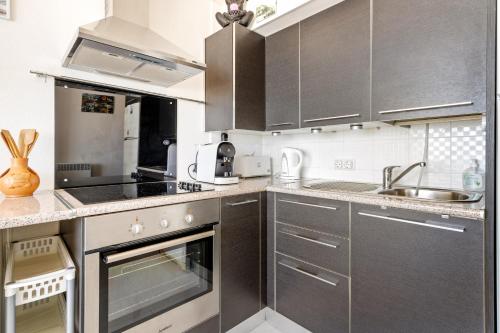 una cocina con electrodomésticos de acero inoxidable y armarios grises en Apartamento Welcs EMP 053 Frente al Mar, en Empuriabrava