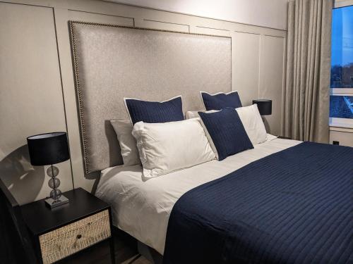 a bedroom with a large bed with blue and white pillows at Sweeney Stays, Cadzow Apartment in Hamilton
