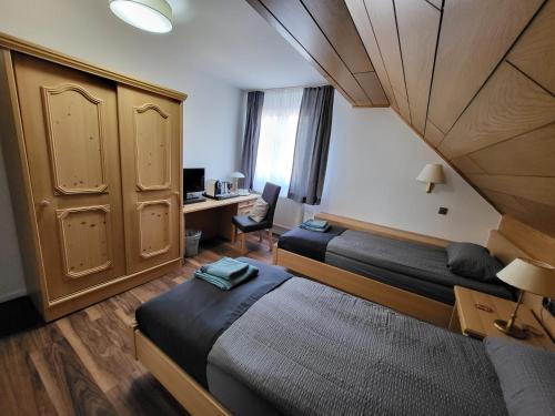 a room with two beds and a desk with a computer at Bergischer Hof - Bergischer Hofgarten in Windeck