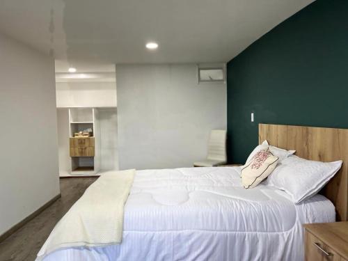 een slaapkamer met een groot wit bed en een groene muur bij Apartamentos céntricos y cómodos en Chapinero in Bogota