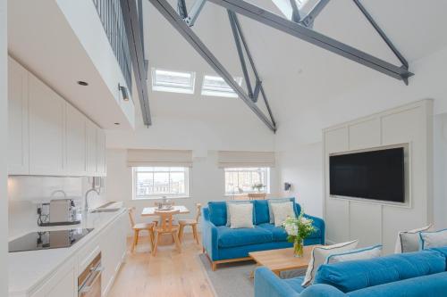 a living room with blue couches and a kitchen at Cheval Old Town Chambers in Edinburgh