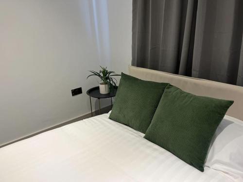 Una cama blanca con almohadas verdes y una planta sobre una mesa en Beautiful and Spacious 2-Bed Apartment: Home Away From Home en South Benfleet