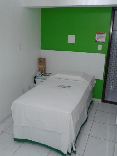 a bed in a room with a green wall at Pousada Maramazon in São Luís