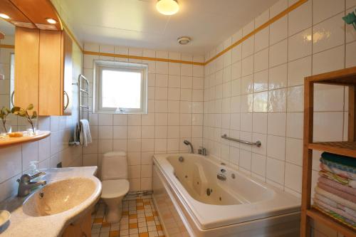 uma casa de banho com uma banheira, um WC e um lavatório. em Cozy cottage with 10 beds near Landvetter em Landvetter