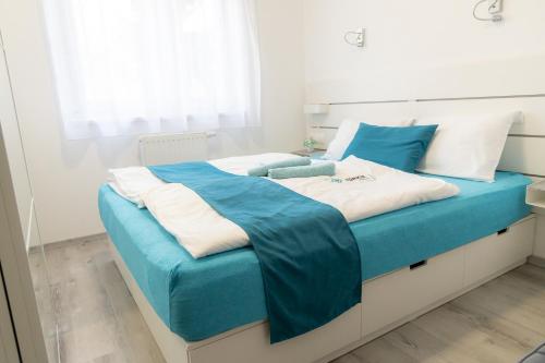 Cama grande con sábanas y almohadas azules y blancas en Türkiz apartman en Kőszeg