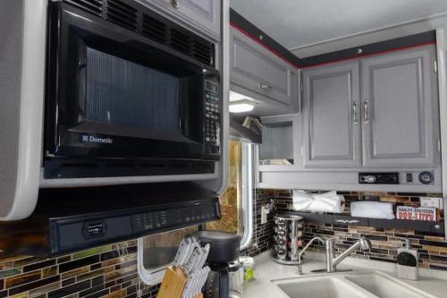 a kitchen with a microwave and a sink at Harley Davidson Ranch Glampling With Kids Play Zone in Ramona