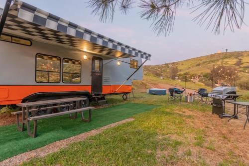 a caravan parked in a field with picnic tables and a grill at Harley Davidson Ranch Glampling With Kids Play Zone in Ramona