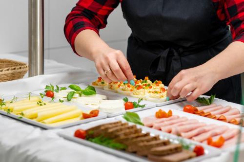 uma pessoa que prepara comida numa mesa com pratos de comida em Wczasowa 8 Apartments em Sarbinowo