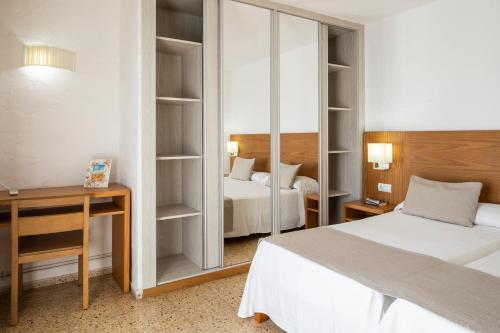 a bedroom with two beds and a desk and a mirror at Apartamentos El Moro in San Antonio