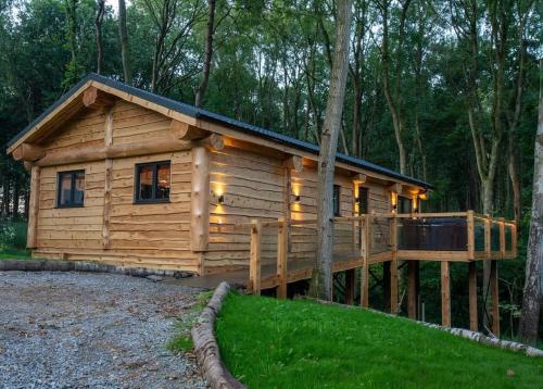 a log cabin with a large deck in the woods at Woodland Park Lodges in Ellesmere