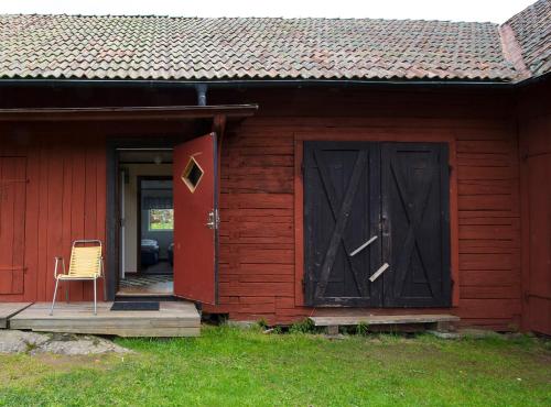 a red barn with a red door and a chair at STF Tivedstorp in Tivedstorp