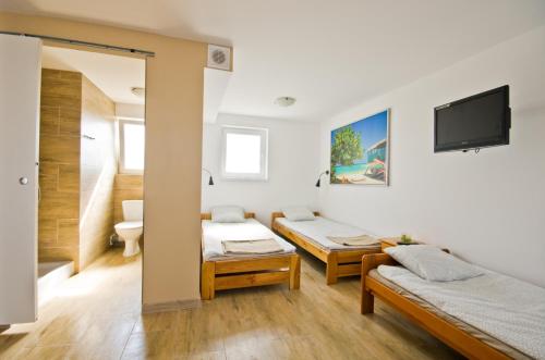 a room with two beds and a tv on the wall at Wind4You in Dąbki