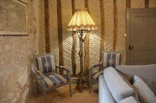 a living room with two chairs and a floor lamp at Le Murmure des Fées in Issigeac