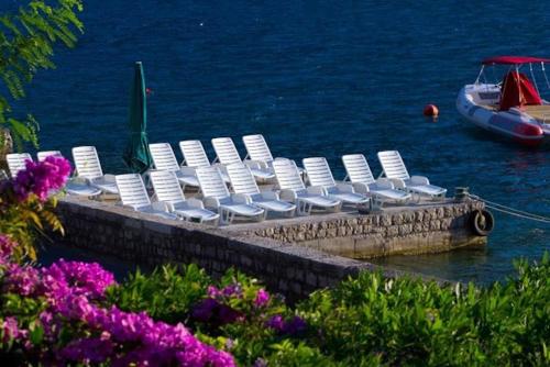 a group of white chairs on a dock in the water at Apartments Iva in Kotor