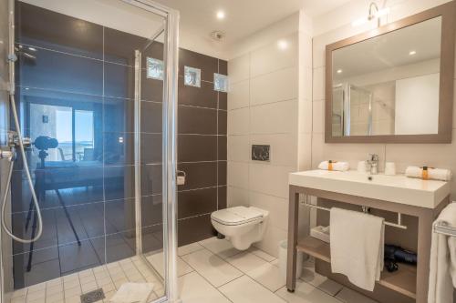 a bathroom with a shower and a toilet and a sink at Hotel Le Grand Pavois in Le Lavandou
