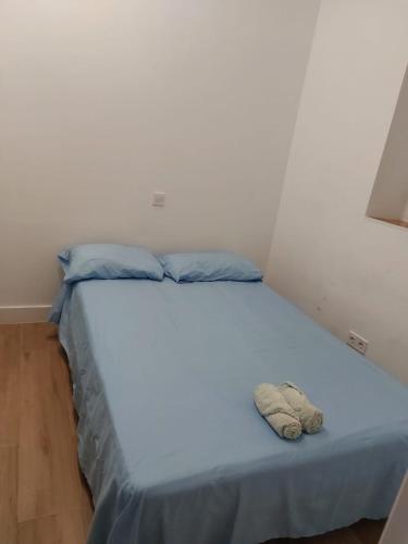 Una cama con sábanas azules y almohadas azules. en Habitación en Madrid, en Madrid