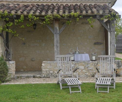 two wooden chairs and a table in a yard at Le Murmure des Fées in Issigeac
