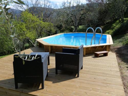 a swimming pool with two chairs and a table on a wooden deck at Holiday Home Il Casale by Interhome in Lama