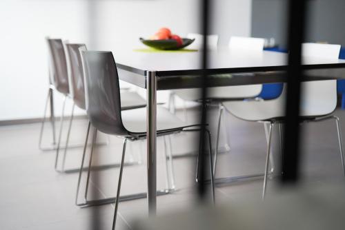 a table with white chairs and a bowl of fruit on it at Max Lodging Serviced Apartments in Munich